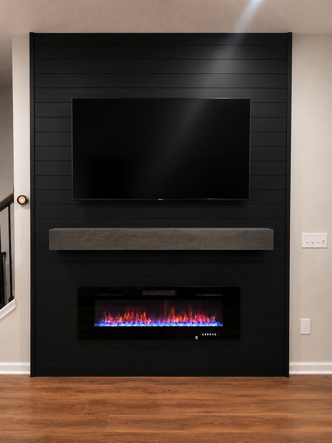 Matte black shiplap wall with recessed electric fireplace and gray mantel