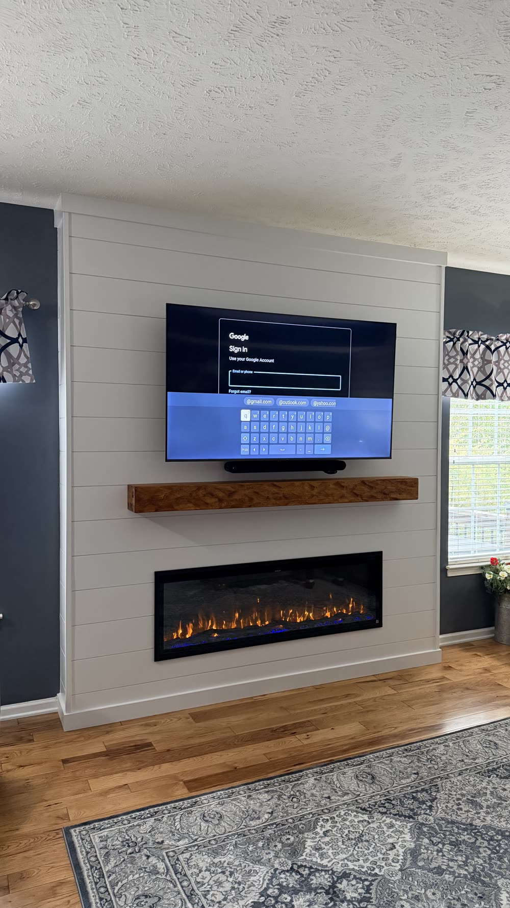 White shiplap wall with dark floating mantel and mounted TV